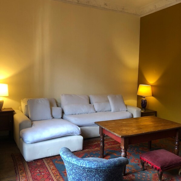 Ein Wohnzimmer mit einer Couch, einem kleinen Tisch, einem gemusterten Sessel und einem Teppich.