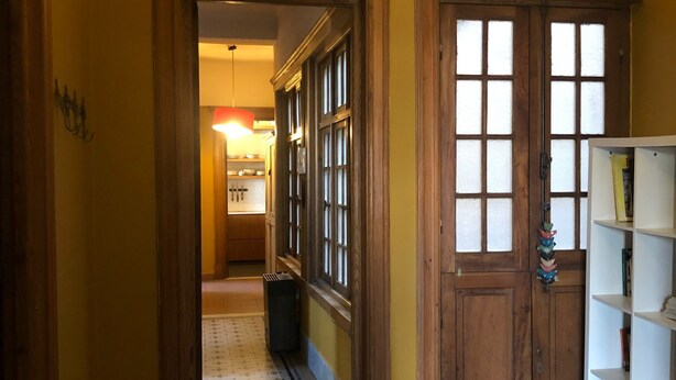 Um corredor com portas de madeira e chão de azulejos.
