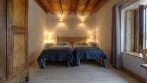 Un dormitorio con dos camas, vigas de madera en el techo, lámparas de noche y una ventana con cortinas.