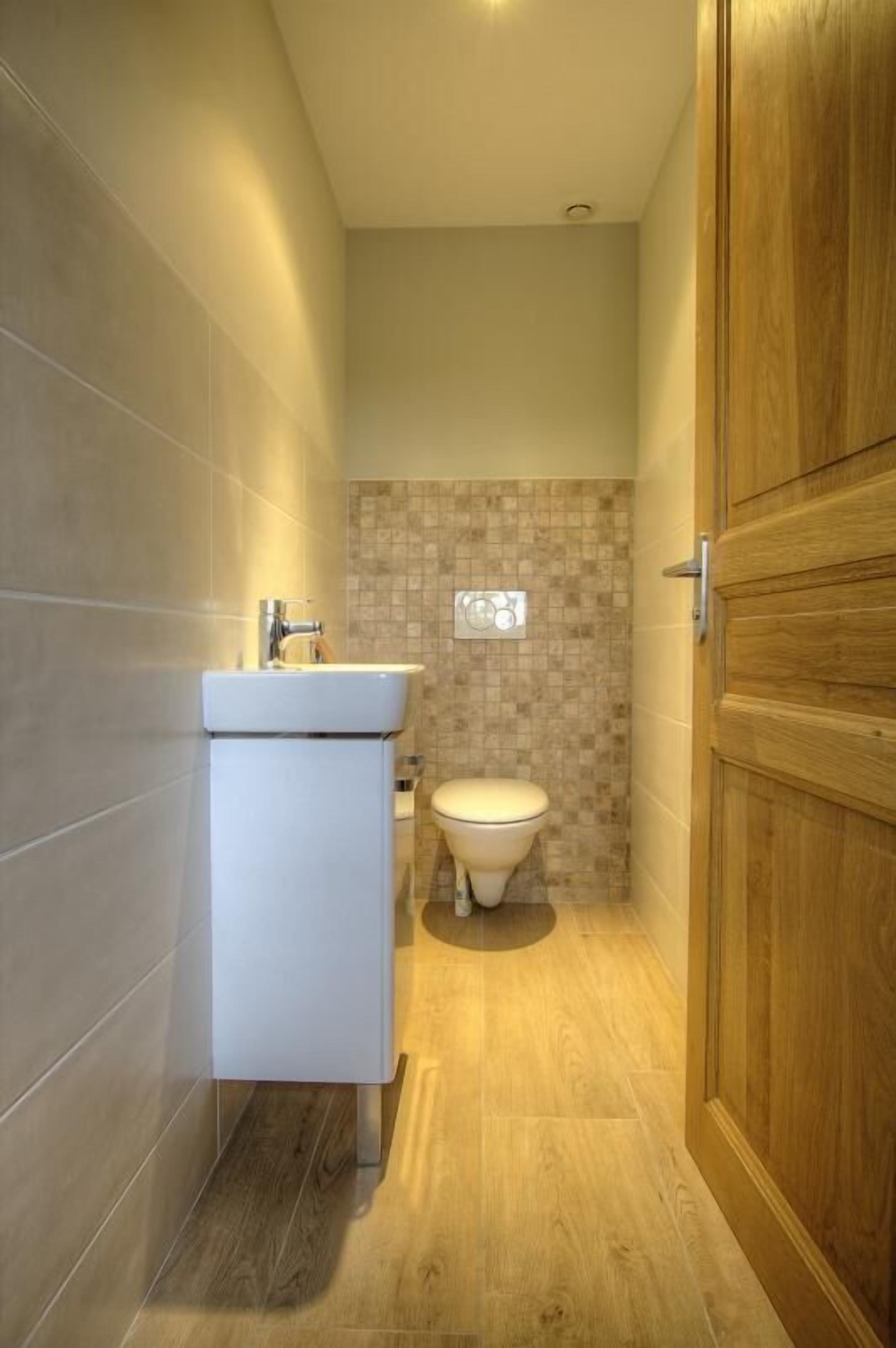Een badkamer met een wit wastafel, toilet en houten deur.
