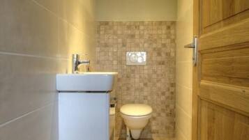 Een badkamer met een wit wastafel, toilet en houten deur.
