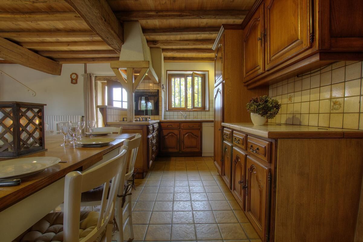 A kitchen with wooden cabinets, a tiled backsplash, and a dining area with a table and chairs.