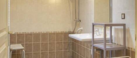 Ein Badezimmer mit Holzboden, einer Dusche, einem Waschbecken und einer Toilette.