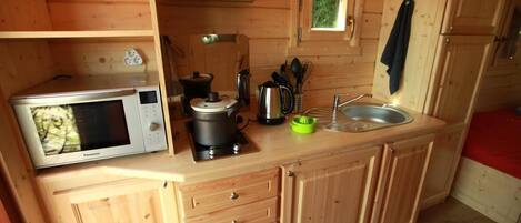 Una cocina de madera compacta con microondas, estufa, lavabo y ventana con vistas.