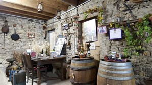 A rustic cellar with stone walls, wooden barrels, and a wooden table with various items.