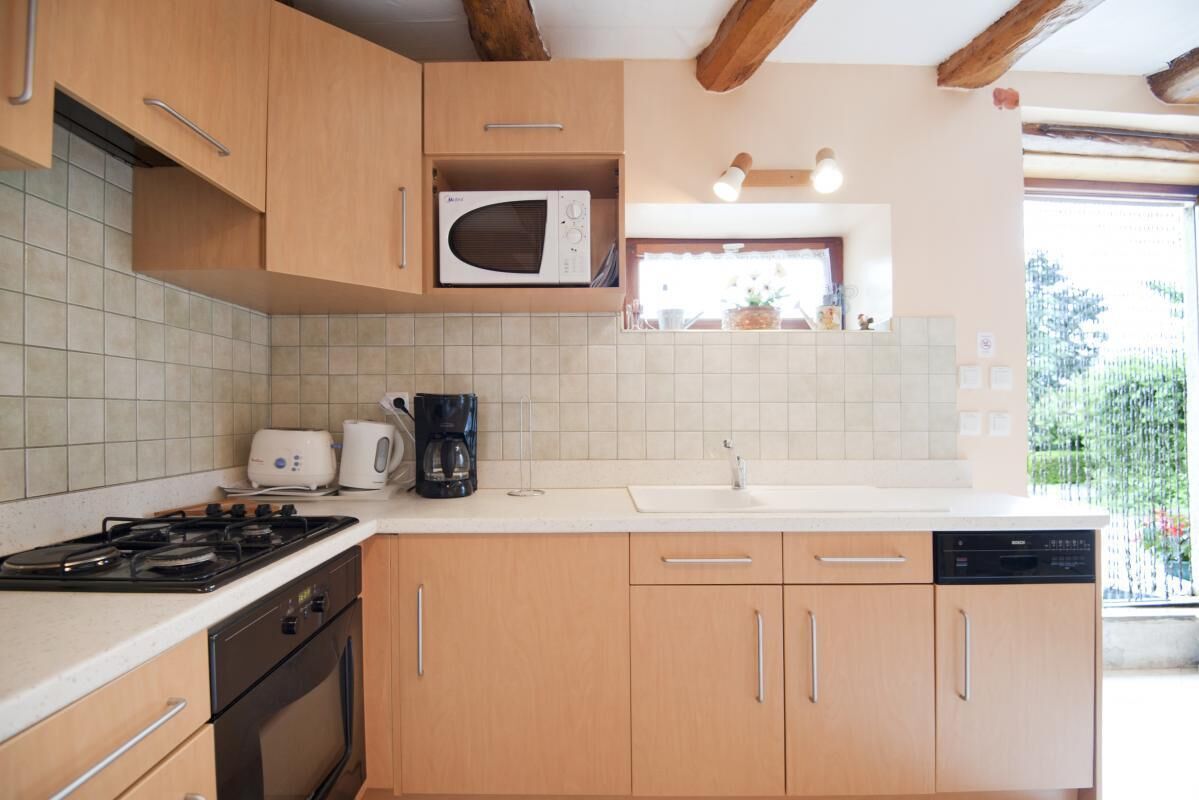 A kitchen with wooden cabinets, a microwave, a stove, a coffee maker, and a dishwasher.