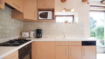A kitchen with wooden cabinets, a microwave, a stove, a coffee maker, and a dishwasher.