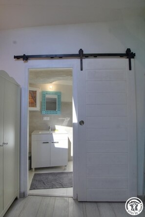Enter a serene space with a sliding door leading to a bathroom featuring a sink and mirror.
