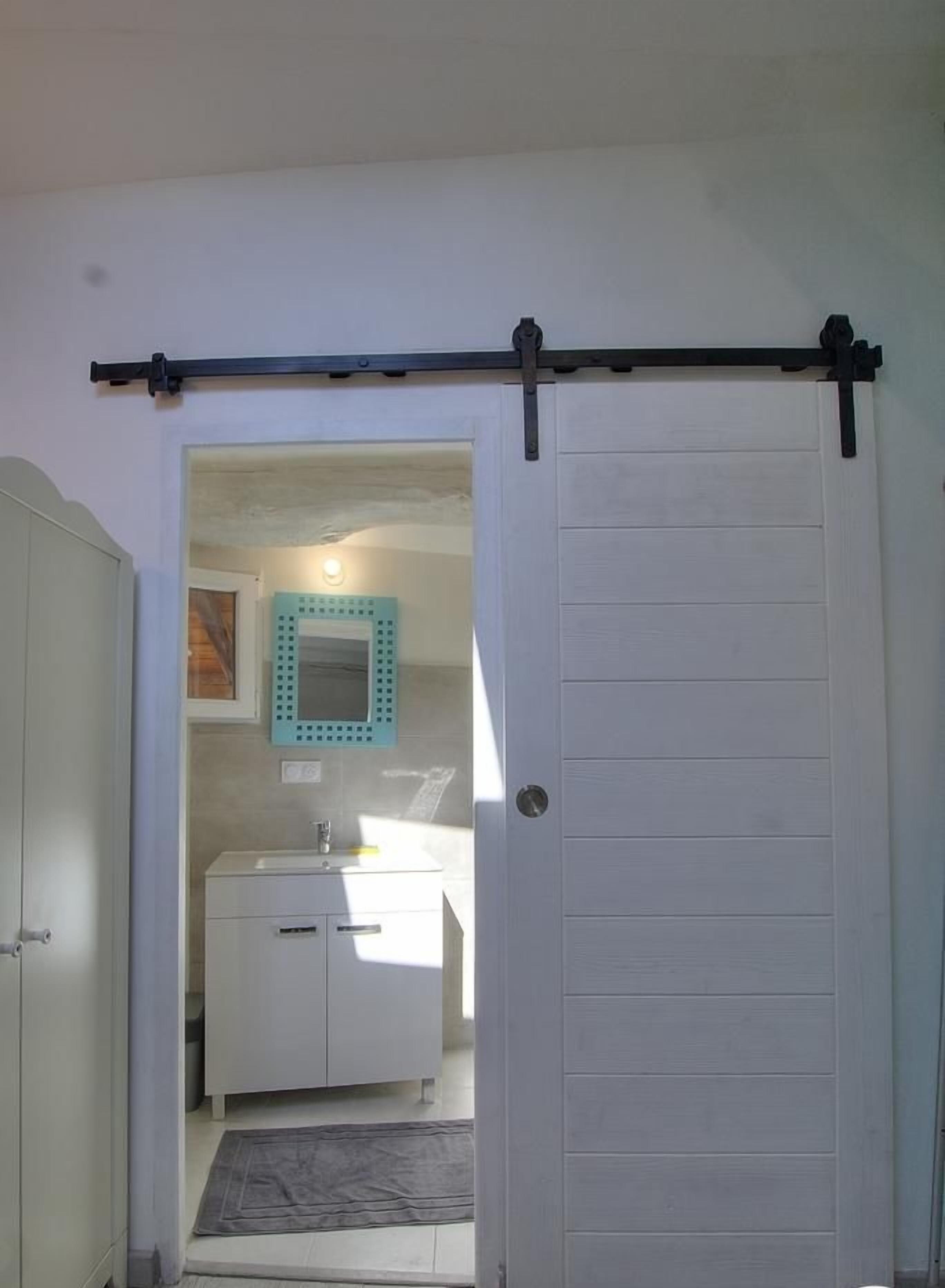 A bathroom with a white door, a mirror, and a sink.