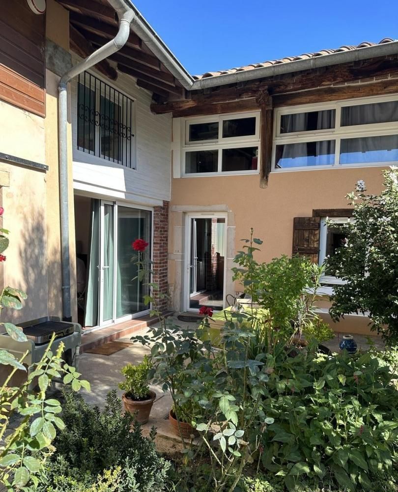 A two-story house with a balcony, a patio area with potted plants, and a sliding glass door.