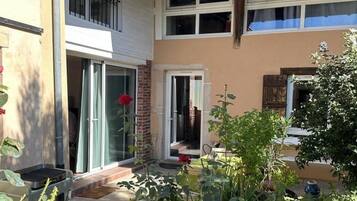 A two-story house with a balcony, a patio area with potted plants, and a sliding glass door.