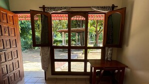 Ein Hotelzimmer mit Bett, Schreibtisch und Fenster mit Blick auf Grünflächen.