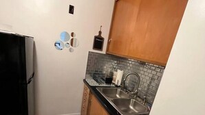 A compact kitchen with a black countertop, stainless steel sink, and wooden cabinets. - 418 W. Main, Apartment #4.

 (Luverne)
