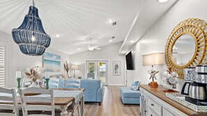 A spacious living room with a dining area, a kitchen with a coffee maker, and a large mirror. - Sunshine House! 3BR 2BA Sleeps 9! Your Perfect Retreat for Comfort and Style (Panama City Beach)