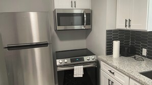 A compact kitchen with a stainless steel refrigerator, a microwave, and a built-in oven. - Cozy two bedroom home minutes from downtown (Houston)