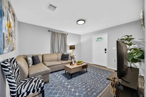 A living room with a sofa, a coffee table, a television, and a patterned rug. - Cozy two bedroom home minutes from downtown (Houston)