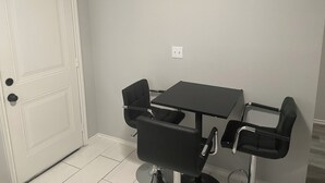 A room with a white door, a black table, and two black chairs. - Cozy two bedroom home minutes from downtown (Houston)