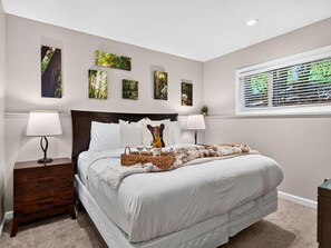 A bedroom with a large bed, two bedside tables with lamps, and a window with blinds.
