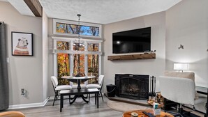 A modern living room with a fireplace, a dining area, and a TV mounted on the wall. - Laurelwood 44 with Wintergreen Advantage (Wintergreen)
