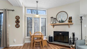 A living room with a fireplace, a dining table with chairs, and a sofa.