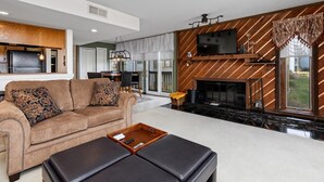 Ein modernes Wohnzimmer mit Sofa, Couchtisch, Kamin, Fernseher und Küchenzeile.