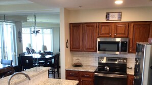 A modern kitchen with wooden cabinets, stainless steel appliances, and a granite countertop.