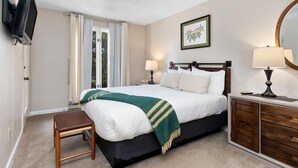 A bedroom with a bed, bedside tables, a television, a window with curtains, and a framed picture on the wall. - Stoneridge 43 with Wintergreen Advantage (Wintergreen)