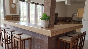 A modern kitchen with a central island, bar stools, and a potted plant. - Villas Rocher (Fond du Sac)