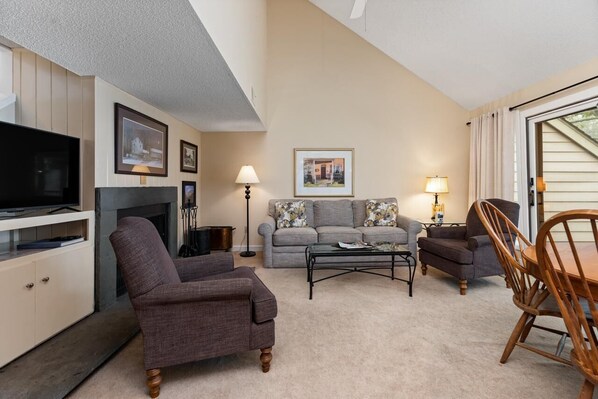 A living room with a fireplace, a television, and a dining area with a table and chairs.
