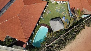 Un resort con varias edificaciones de techo rojo, una piscina y un césped bien cuidado con mobiliario exterior.