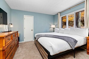 Relax in this serene bedroom with a large bed and views of the surrounding autumn foliage.