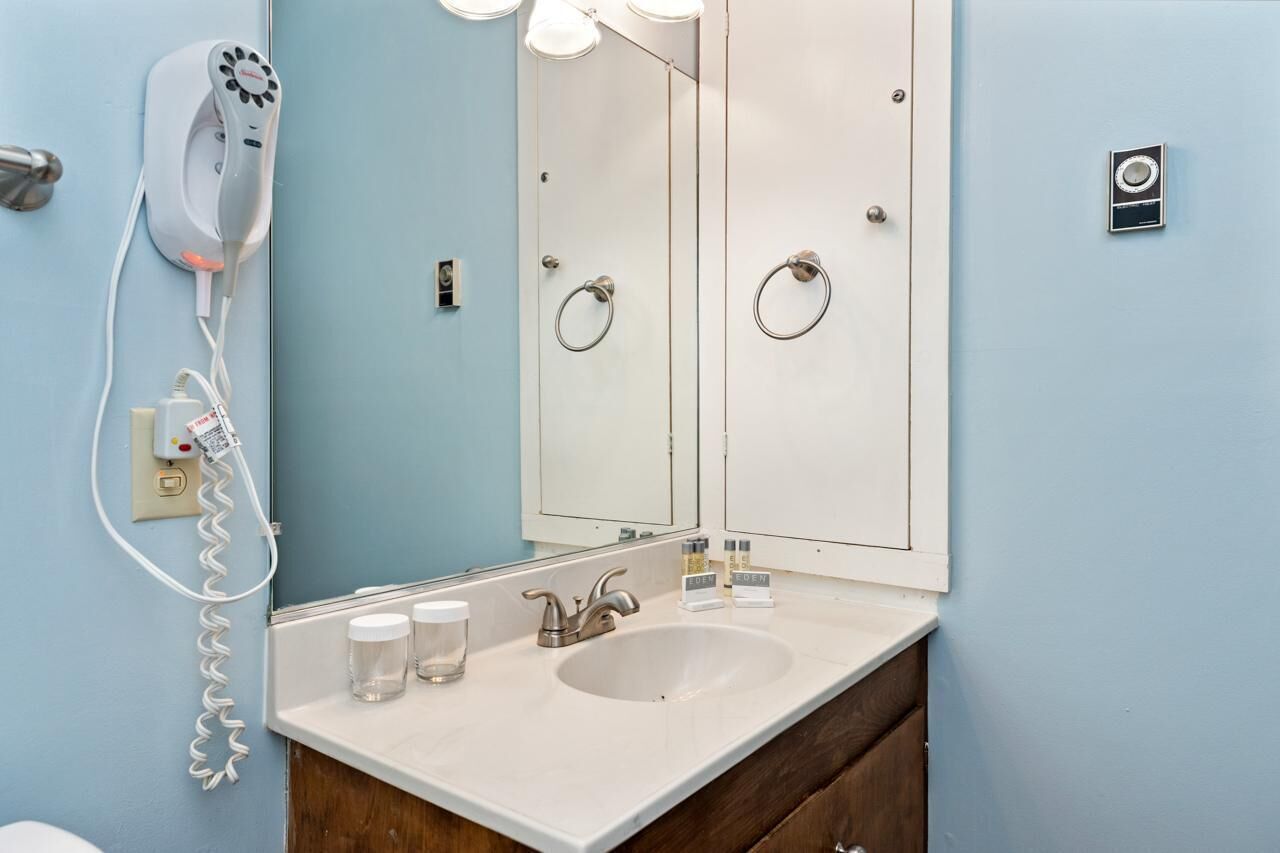 Un baño con un lavabo blanco, un secador de pelo y un espejo.