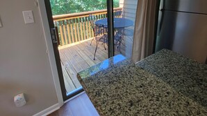 Una cocina con encimera de granito, una puerta corrediza de vidrio que da a una terraza y un refrigerador.