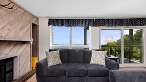 A living room with a dark grey sofa, patterned throw pillows, a wooden coffee table, and a fireplace. - Highlands 05 with Wintergreen Advantage (Wintergreen)
