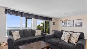 A living room with two grey sofas, a wooden coffee table, and a large window with a view of the outdoors. - Highlands 05 with Wintergreen Advantage (Wintergreen)