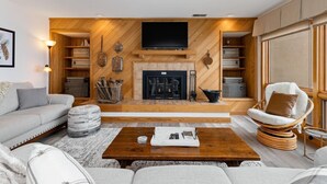 Una sala de estar moderna con chimenea, estantes de madera y televisor.