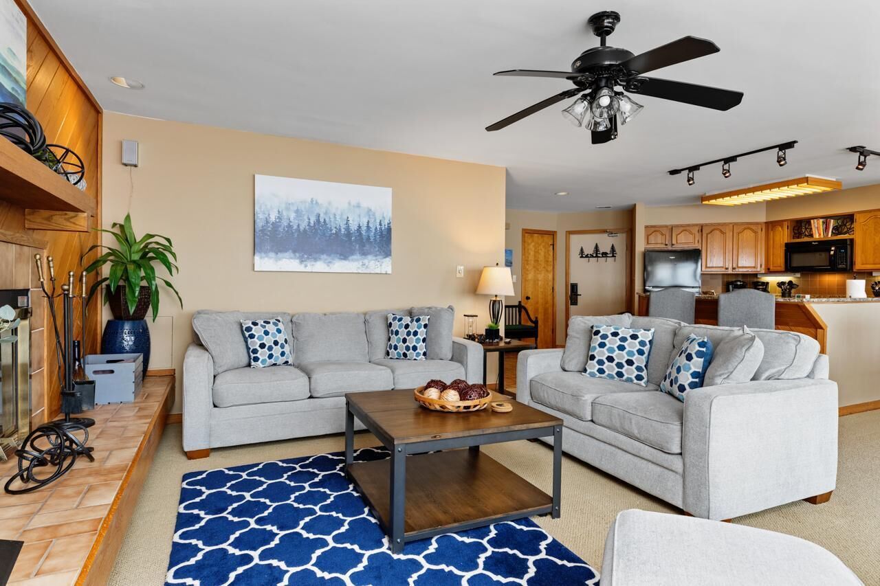 A modern living room with two grey sofas, a coffee table, and a ceiling fan.