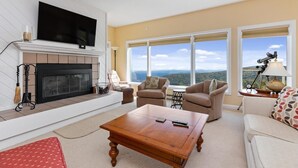 A living room with a fireplace, a television, and large windows offering a view of the landscape. - Overlook 43 with Wintergreen Advantage (Wintergreen)