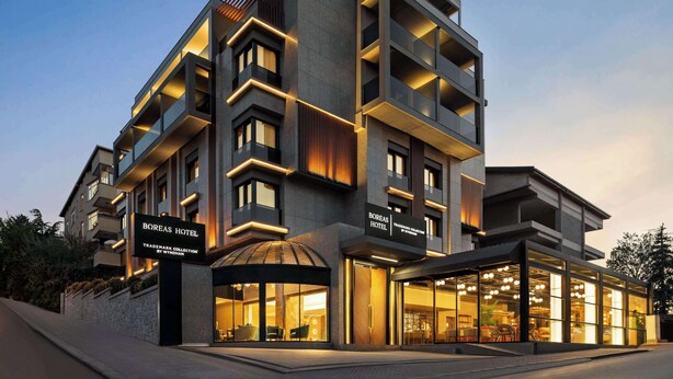 A modern hotel with a multi-story structure, large glass windows, and a well-lit entrance. - Boreas Hotel & SPA, Trademark Collection by Wyndham (Ankara)