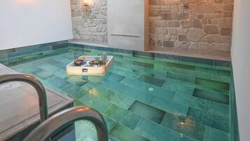 Un área de piscina en la azotea con tragaluces, paredes de piedra y un espacio para sentarse.