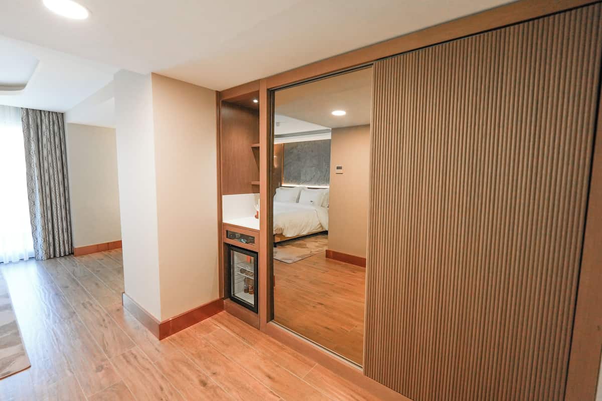 Ein Hotelzimmer mit einer Schiebetür zu einem Schlafbereich, einer eingebauten Minibar und einem Holzboden.