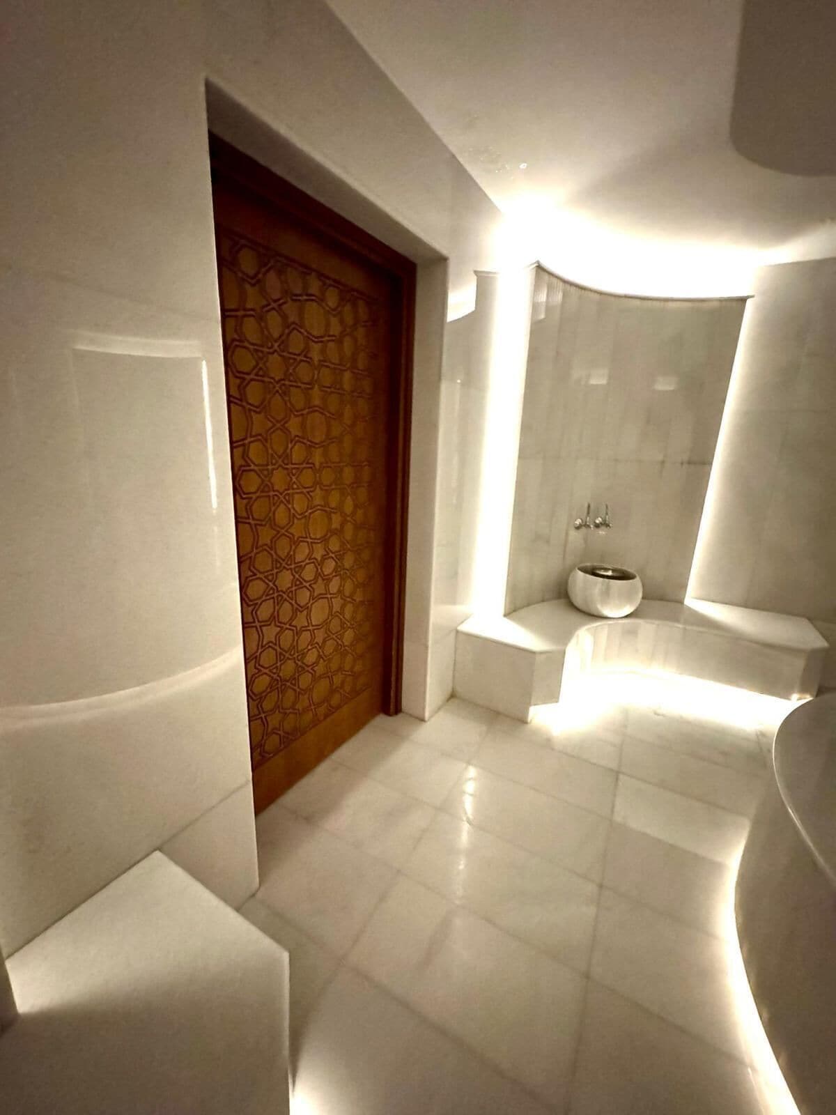 Un baño moderno con una puerta de diseño geométrico, un lavabo blanco y una pared curva.