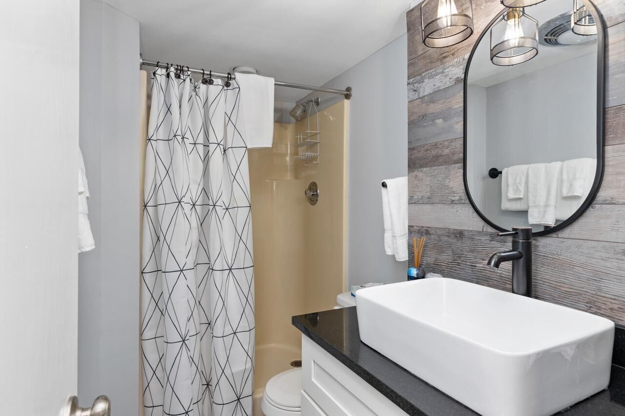 Un baño moderno con ducha, lavabo blanco y espejo.