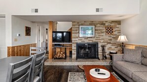 Ein modernes Wohnzimmer mit Kamin, Fernseher und Essbereich mit Holztisch und Stühlen.
