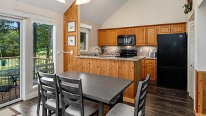 Eine moderne Küche mit Holzausstattung, einem schwarzen Kühlschrank und einer Arbeitsplatte aus Granit.