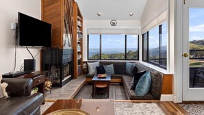 Una sala de estar amplia con chimenea, un ventanal con vistas al exterior y un televisor de pantalla plana en la pared.