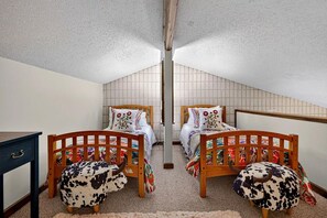 A mirrored room with two beds, a desk, and a chair.