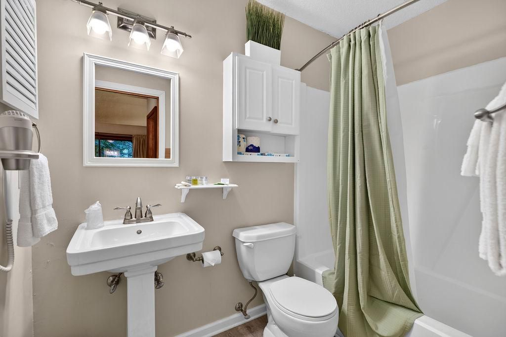 Baño con lavamanos, inodoro y cortina de ducha.