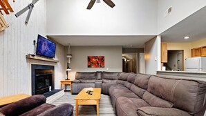 Una sala de estar moderna con un sofá modular, una chimenea, un televisor y un comedor.
