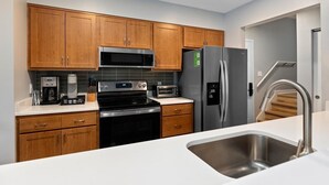 A modern kitchen with wooden cabinets, stainless steel appliances, and a white countertop. - Stoneridge 69 with Wintergreen Advantage (Wintergreen)